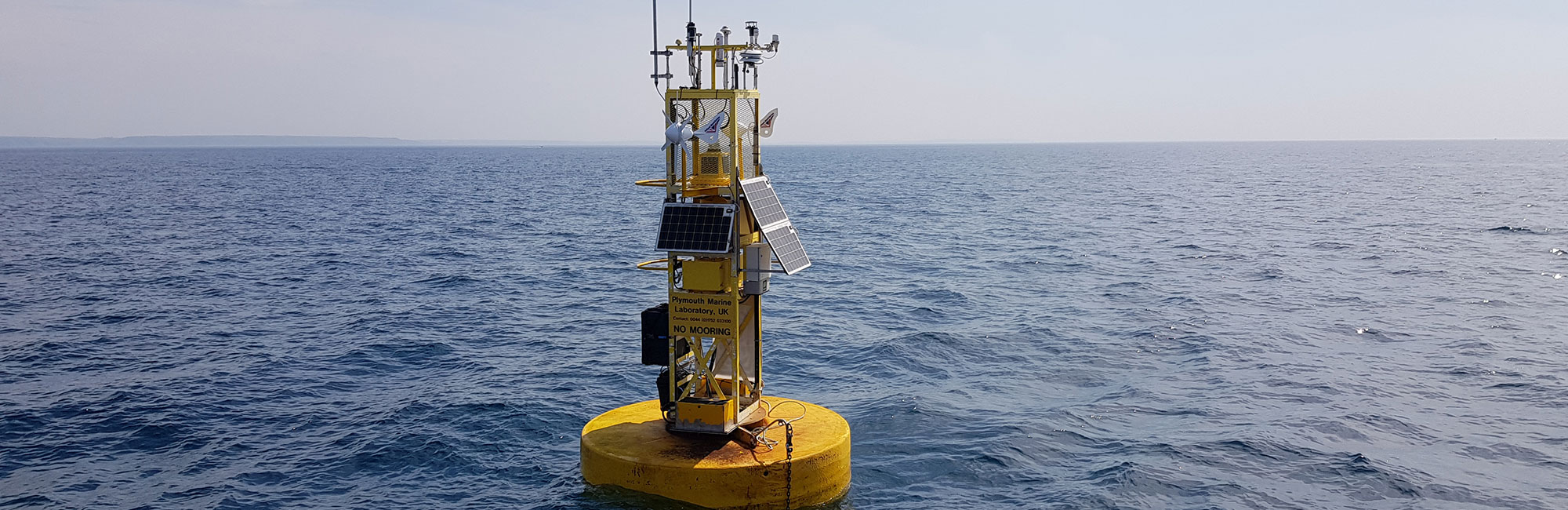 Picture of a yellow scientific data buoy at sea